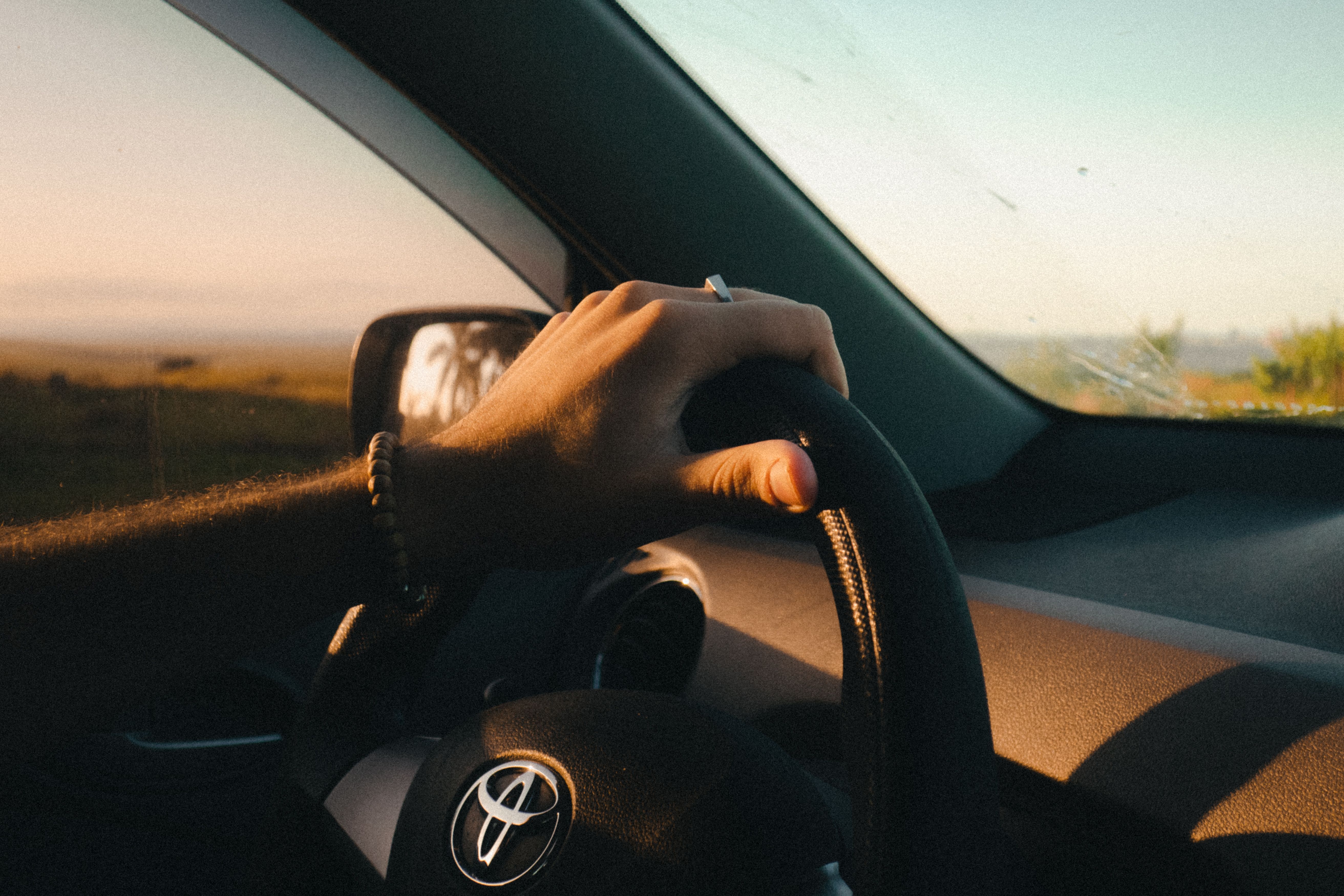Persona manejando su auto al atardecer